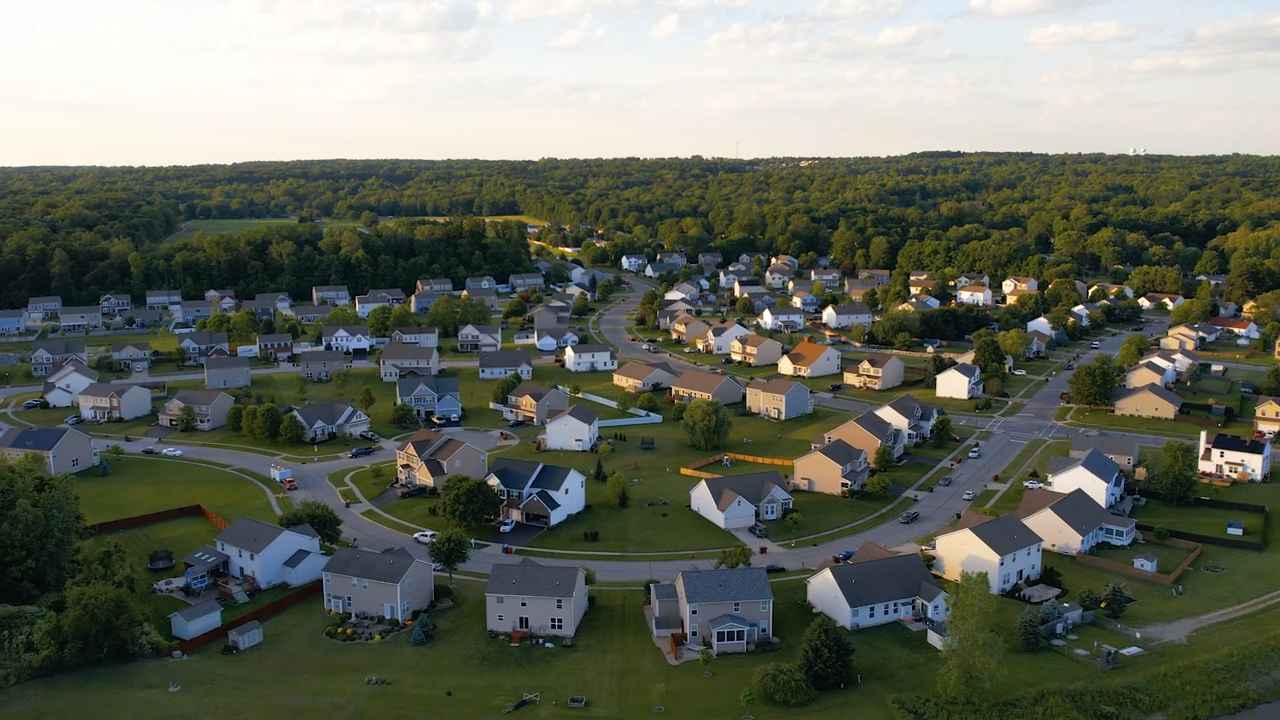Aerial view of a residential neighborhood with houses and streets bordered by forested areas